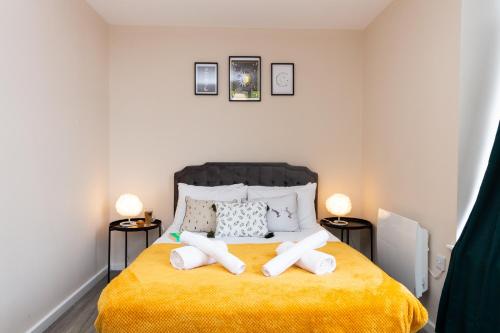 a bedroom with a yellow bed with two towels on it at Stylish Living: 1BR Apt near MCR Central in Manchester