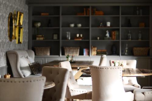 une salle à manger avec des chaises blanches, une table et des étagères dans l'établissement Gällöfsta Konferens & Herrgård, à Kungsängen