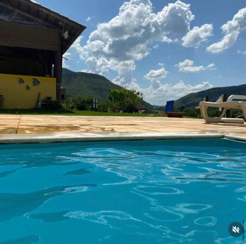 a blue swimming pool in front of a house at Pousada valle do chalé in Capitólio