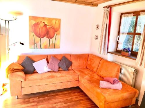 a living room with an orange couch with pillows at Wohnung in Hauzenberg mit Terrasse, gemeinsamem Pool und Garten in Hauzenberg