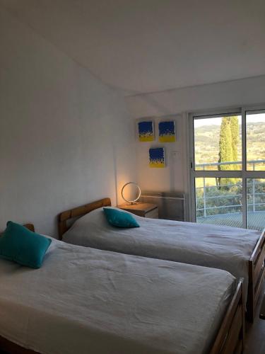 deux lits dans une chambre avec une fenêtre dans l'établissement L'Amiradou , La Cadiere D Azur, à Saint-Côme