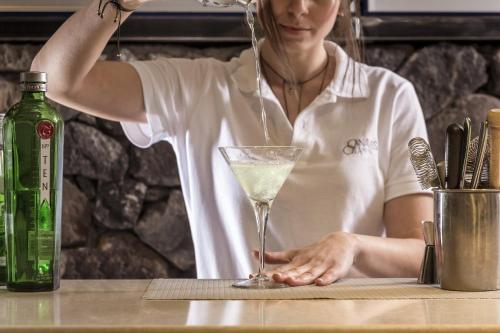 a woman pouring a drink into a martini glass at Canaves Oia Suites & Spa in Oia