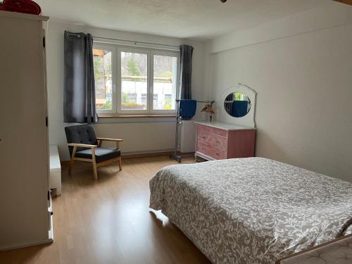 a bedroom with a bed and a chair and a window at Les Rossets in Boudry