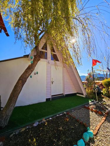 a small house with a tree and a red flag at Lushtree Backpackers - Hostel & Cafe in Mukteswar