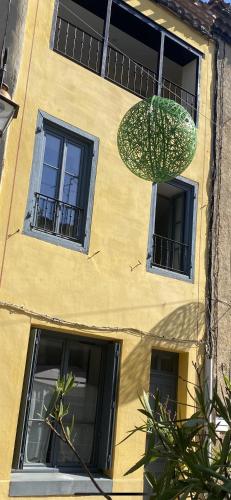 un bâtiment jaune avec trois fenêtres et un ventilateur dans l'établissement Au pied de La Cité, piscine, vue extraordinaire, gîte La Trivala, à Carcassonne