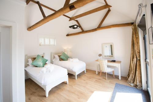 a bedroom with two beds and a desk at Great Blunts Stables in Billericay