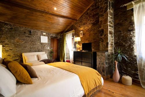um quarto com uma cama e uma parede de pedra em Casa da Serra - Mountain Home em Arganil