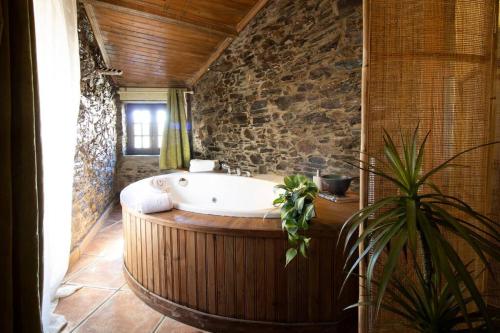 y baño con bañera en una pared de piedra. en Casa da Serra - Mountain Home, en Arganil