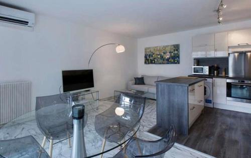 Il dispose d'une cuisine et d'un salon avec une table et des chaises en verre. dans l'établissement LOVELY 1BR-CANNES CENTER, à Cannes