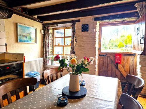 a dining room table with a vase of flowers on it at Y Beudy Llangrannog in Llangrannog