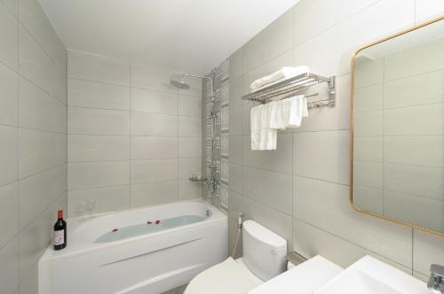 a bathroom with a tub and a toilet and a sink at Harry Phu Quoc Hotel in Phú Quốc
