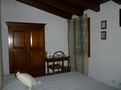 1 dormitorio con 1 cama, puerta de madera y silla en B&B La Villa del Vecchio Platano, en Vigonovo