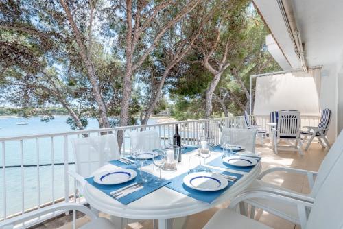 una mesa blanca y sillas en un balcón con vistas al agua en Ferienwohnung für 6 Personen ca 100 qm in Portocolom, Mallorca Südostküste von Mallorca, en Portocolom