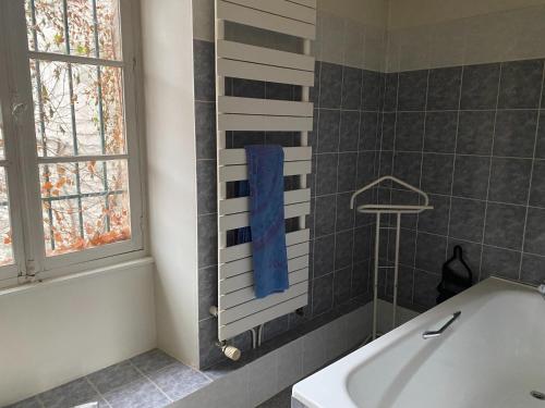 baño con bañera, ventana y toalla azul en La Grande maison, en Chambon-sur-Voueize