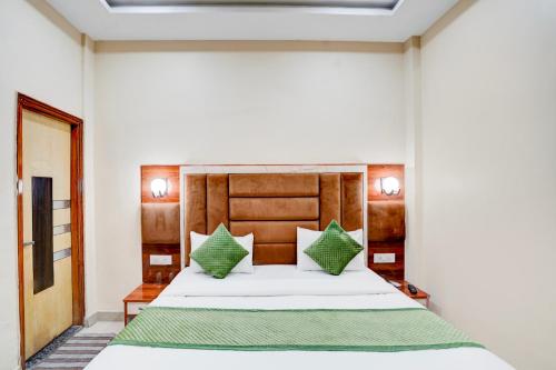 a bedroom with a large white bed with green pillows at Yoga Homestay in Agra
