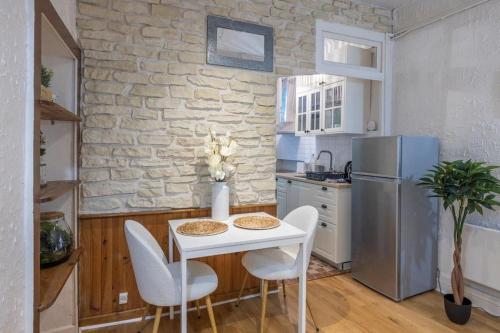 une cuisine avec une table, des chaises et un réfrigérateur dans l'établissement Appartement cosy dans les rues piétonnes, à Grenoble