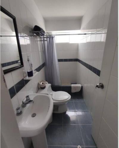 a bathroom with a white toilet and a sink at La Habitación de Isolina in Lima