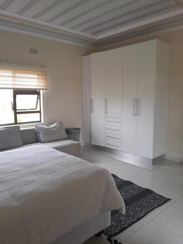 a white bedroom with a large bed and a window at PHIL M AND PARTNERS ESTATES. in Manzini