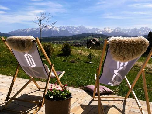 two folding chairs sitting on a patio with mountains in the background at Zagroda Rusiński in Bukowina Tatrzańska