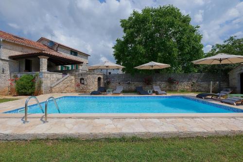 una piscina frente a una casa con sombrillas en Ferienhaus mit Privatpool für 8 Personen ca 250 qm in Klarici, Istrien Binnenland von Istrien en Butkovići