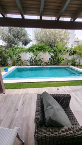 un divano seduto di fronte alla piscina di Belle maison à proximité de la mer a La Marsa