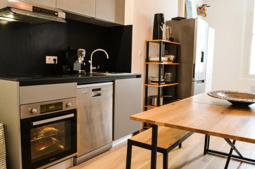 La cuisine est équipée d'une table, d'une cuisinière et d'un réfrigérateur. dans l'établissement Le Cabanel - Climatisation en centre ville, à Montpellier
