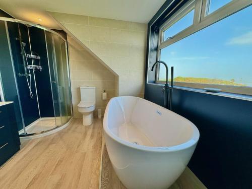 a bathroom with a large white tub and a toilet at High Auchenlarie Cottage in Gatehouse of Fleet