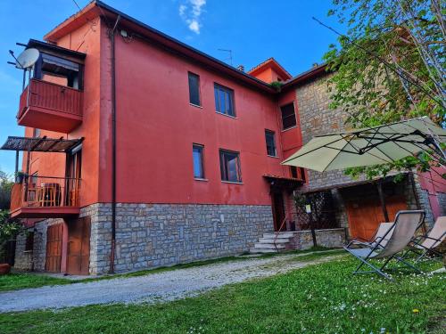 een rood gebouw met twee stoelen en een paraplu bij Appartamento vacanze in Ravigliano