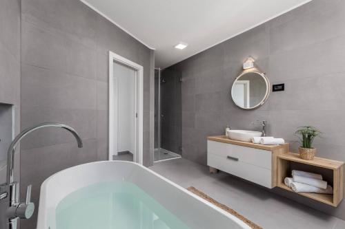 La salle de bains est pourvue d'une baignoire, d'un lavabo et d'un miroir. dans l'établissement Luxury Villa Amataa - 38m2 pool, jacuzzi, sauna, à Mošćenička Draga
