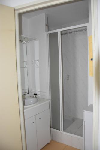 uma casa de banho branca com um chuveiro e um lavatório. em Appartement 1 chambre, avec loggia et vue sur le Port Olona em La Chaume