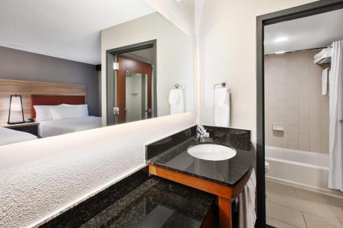 a hotel bathroom with a sink and a bed at Candlewood Suites - Cincinnati Northeast - Mason by IHG in Mason