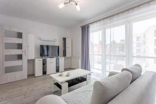 sala de estar blanca con sofá y TV en Ferienwohnung am Meer, Urlaub auf der Insel Usedom, Apartment Flotylla 13, en Świnoujście