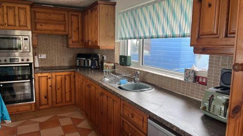 a kitchen with wooden cabinets and a sink and a window at The Beach House in Newry