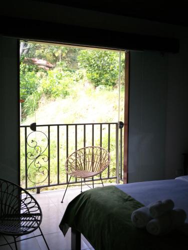 a bedroom with a bed and a balcony with a chair at ROCCA VENTO in Bajo Boquete