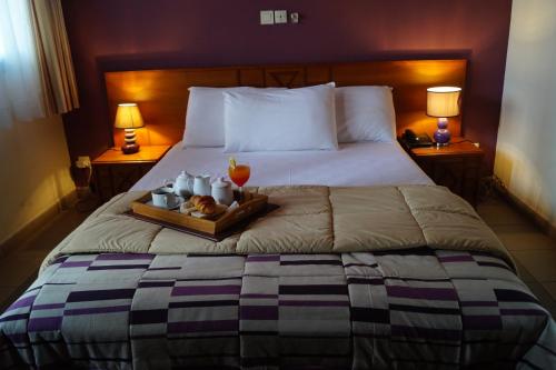 Una cama con una bandeja de comida y bebidas. en Hôtel Sol Béni en Abiyán