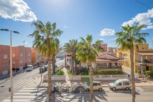 a street with palm trees and cars in a city at Beach View Apartment Santa Pola in Santa Pola