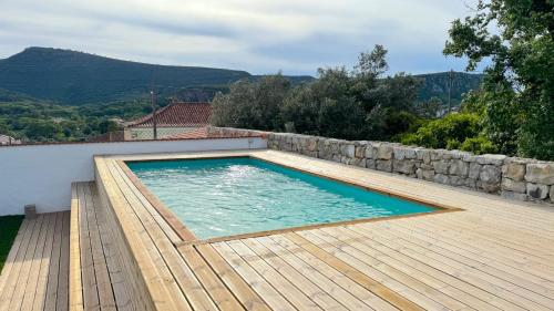 a swimming pool with a wooden deck and a wall at Casa de Alcaria in Alcaria