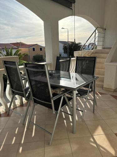 a glass table and chairs on a balcony at Apartman J&B in Vir