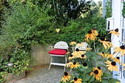 uma cadeira com uma almofada vermelha sentada ao lado de alguns girassóis em Appartement Relax in Welferode mit Großer Terrasse em Welferode