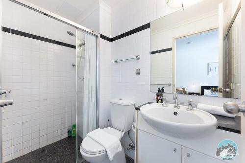 Baño blanco con lavabo y aseo en Aircabin - Sydney Central Station - 1 Bed Studio en Sídney