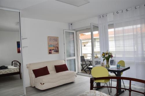 un salon avec un canapé blanc et une table dans l'établissement Les Grandes Roches - Studio et balcon plage à pied, à La Rudelière