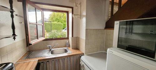 une petite cuisine avec un évier et une fenêtre dans l'établissement La clef des chants, à Longueville
