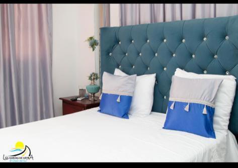 a large bed with a blue headboard and white pillows at Hotel las marias de neiba in Cerro en Medio