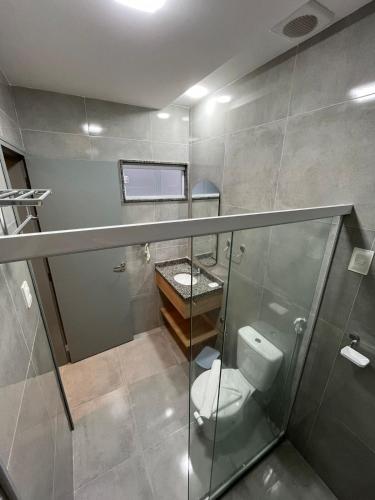 a bathroom with a toilet and a glass shower at Hotel Place Jardin in Garanhuns