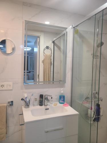 a white bathroom with a sink and a shower at Playa Flamenca Splendid apartment on the beach in Alicante
