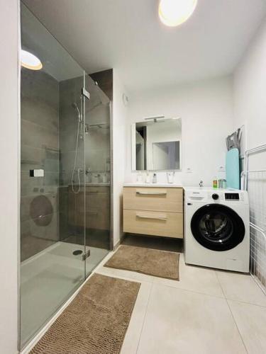 La salle de bains est pourvue d'un lave-linge et d'une douche. dans l'établissement Appartement centre avec jardin-400m plage, à Concarneau