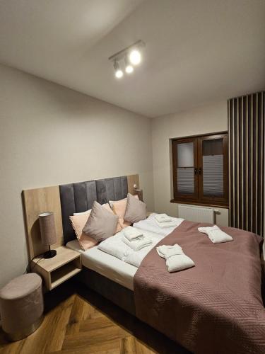 a bedroom with a large bed with two towels on it at Apartament B6 Green Resort z Basenem, Sauną, Jacuzzi - 5D Apartments in Szklarska Poręba