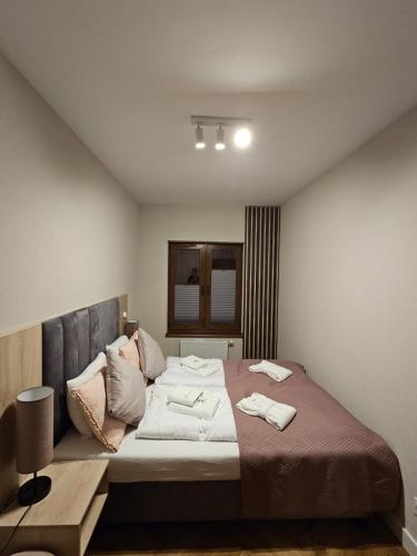 a bedroom with a large bed with two towels on it at Apartament B6 Green Resort z Basenem, Sauną, Jacuzzi - 5D Apartments in Szklarska Poręba