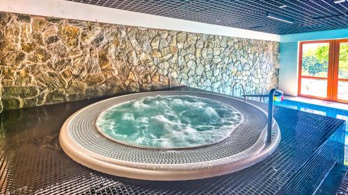 a hot tub in a room with a stone wall at Apartament B6 Green Resort z Basenem, Sauną, Jacuzzi - 5D Apartments in Szklarska Poręba
