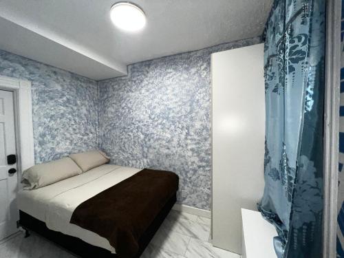 um quarto com uma cama num quarto com papel de parede azul em 3 bedrooms in Modern Brooklyn home, Close to J train em Brooklyn